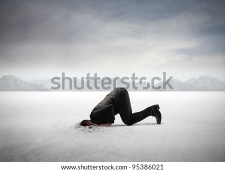 Businessman hiding his head in the sand