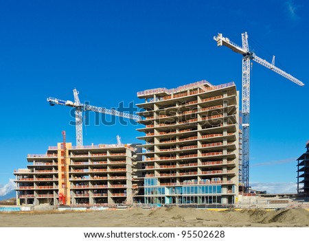 High-rise building construction site with cranes against blue sky