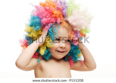 Little boy in colorful bright wig holding his head laughing