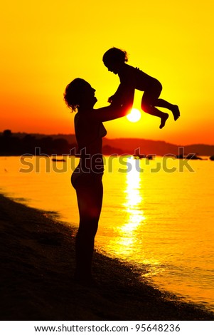 Silhouette of mother and child in a sunset near the water