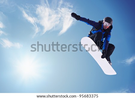 Snowboarder jumping against blue sky Royalty-Free Stock Photo #95683375