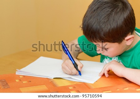 small school boy writing homework from school in workbook Royalty-Free Stock Photo #95710594
