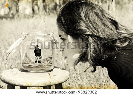 girl looks at herself in the glass jar. Photo in old image style.