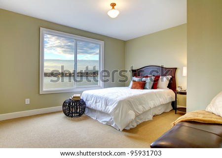 Green green bedroom with water view and white bedding.