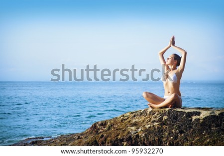 Young woman on a beach doing yoga