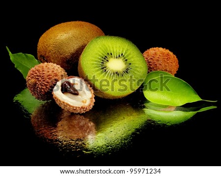 kiwi and lychee fruits with leaves on a black background with water drops
