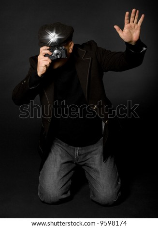 Retro style photographer with vintage camera and flash holding up his hand taking a picture
