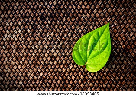 a green betel leaf on brown woven  texture background