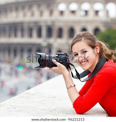 Portrait of a pretty young tourist taking photographs while sightseeing in Rome, Italy (with Colosseum in the background)