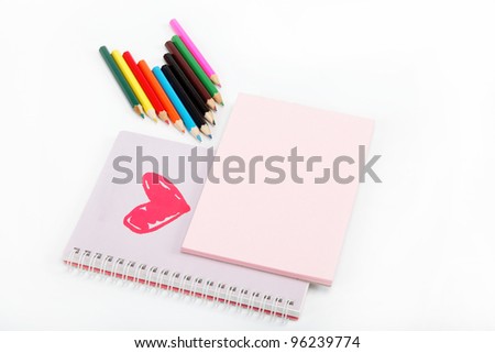 Notebook and colored pencils on a white background.