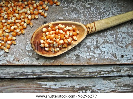 Pile of corn grains with a wooden spoon on old retro wooden background with cracks