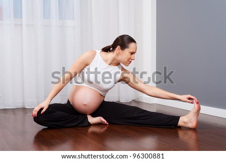 beautiful pregnant woman doing gymnastic at home