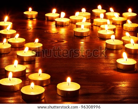 Group of burning candles on  black background.