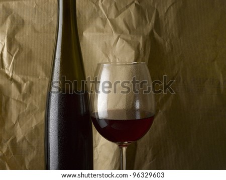 Bottle and glass of red wine with brown paper background
