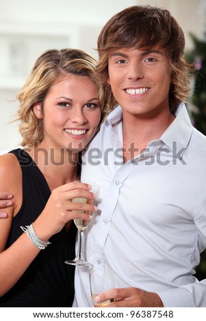 Young couple stood at home with champagne flutes