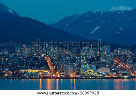 City at night, panoramic scene reflected in water, North Vancouver, Canada.