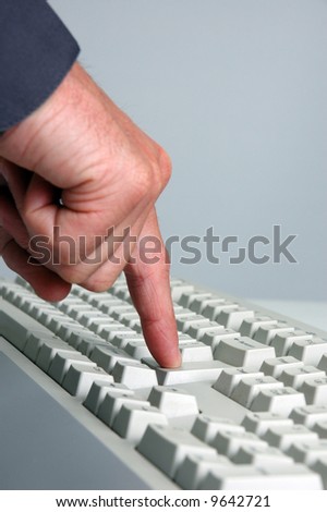 Man's hand pressing the "Enter" key on a computer keyboard.