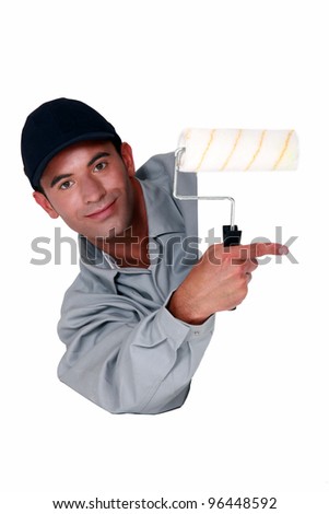 Tradesman holding a paint roller and pointing to a blank sign