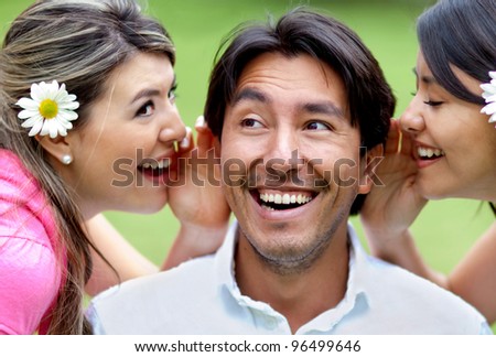 Portrait of women telling a secret to a man - outdoors