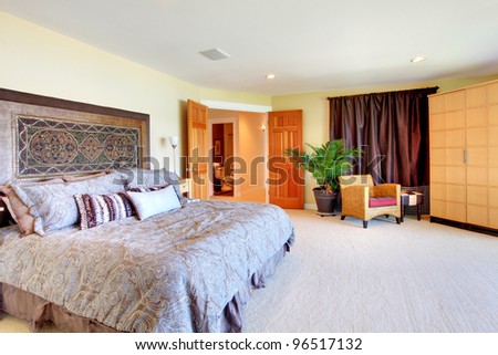 Beautiful large master bedroom with grey bed and chair.