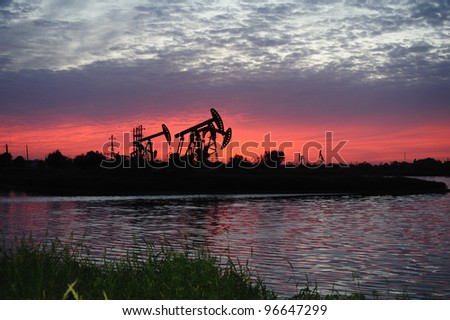 Working oil pump in grassland at sunset