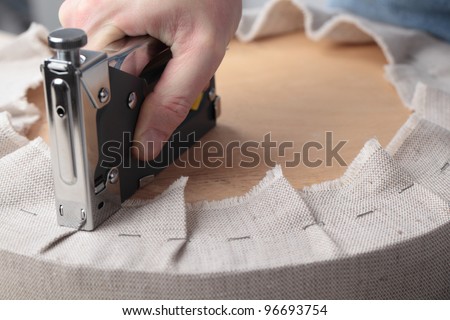 Man upholstering a round stool seat Royalty-Free Stock Photo #96693754