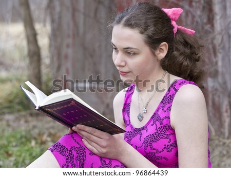 Young teen girl reading in the park