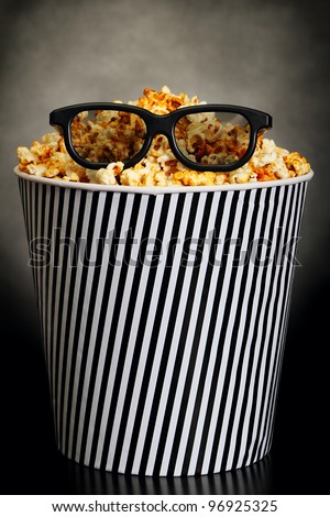 Popcorn in a box with HD cinema glasses on black background