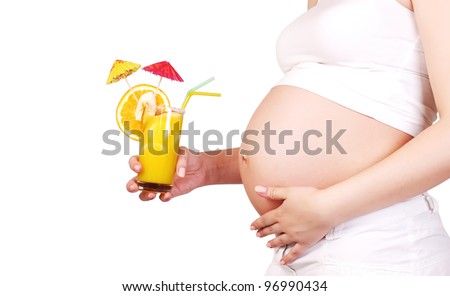 Closeup image of pregnant woman tummy with glass of fruit cocktail in hand