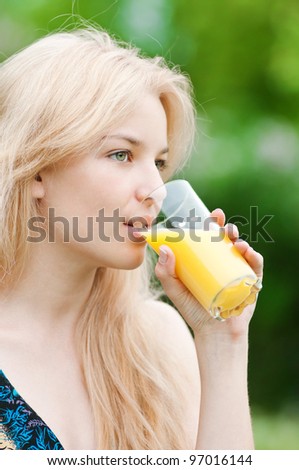 Young happy smiling woman drinking orange juice outdoor