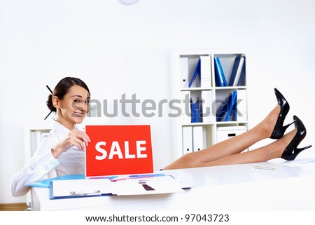Young woman sitting in office in business wear with sale sign