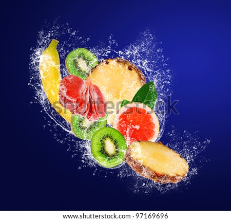 Sliced tropical fruit falling in water splahes on dark blue background