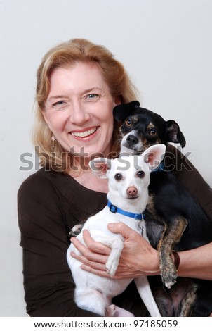 Smiling woman holding two small dogs. Isolated on white.