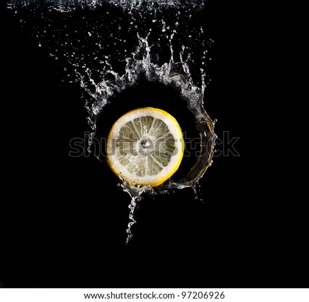 Lemon falling into water on black background