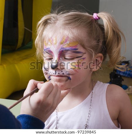 Little girl having face painted on birthday party Royalty-Free Stock Photo #97239845