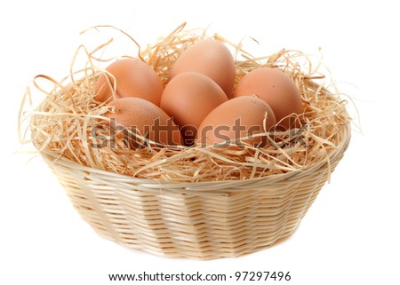 Brown eggs at hay in the basket on white