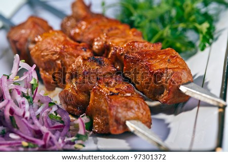 fresh portion of shish kebab on plate with onion and greens Royalty-Free Stock Photo #97301372