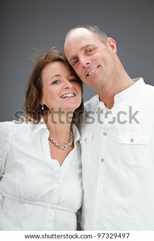 Studio portrait of middle aged couple wearing white shirt isolated on grey background