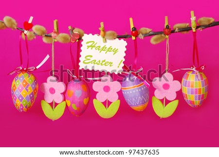 easter border with hanging colorful eggs and  felt flowers against pink background
