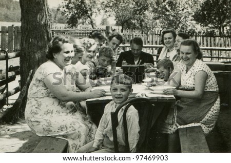 Vintage photo of big happy family dining outdoor (fifties)
