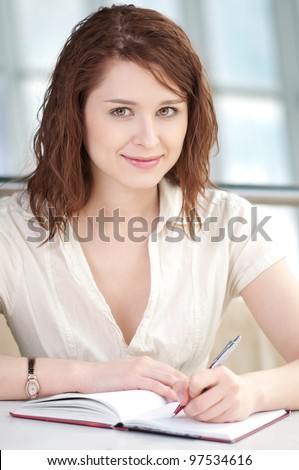 Smiling young business woman taking notes in office