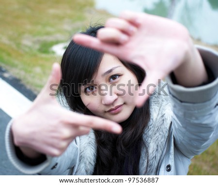 Pretty girl having fun outdoor, making frame with hands, taking picture with imaginary camera, selective focus