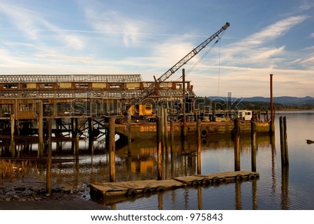 Photo of a boat landing, ruins of a net shed, and floating crane taken from the Yacht Club in Astoria, Oregon