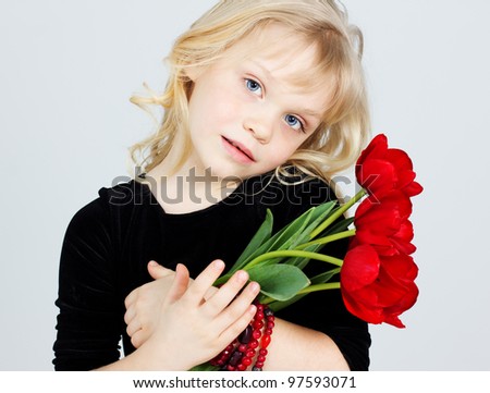 Portrait of a sunny child girl with bouquet of red tulips