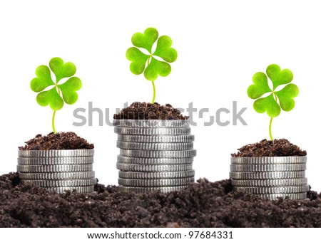 Money growth. Silver coins in soil with clover leaves. Financial metaphor.