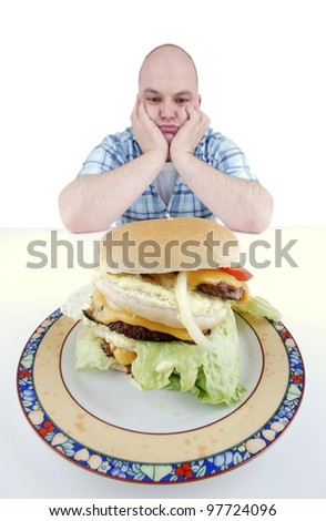 unhappy looking man stares at a big cheeseburger