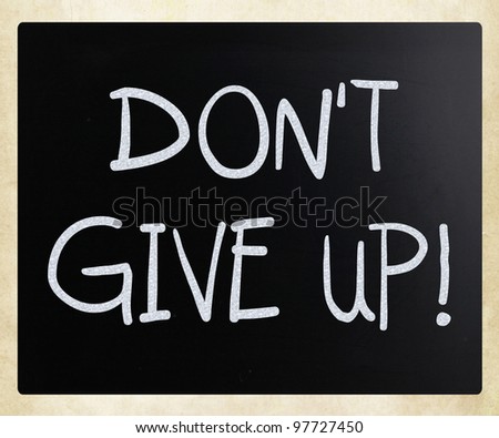 "Don't give up" handwritten with white chalk on a blackboard