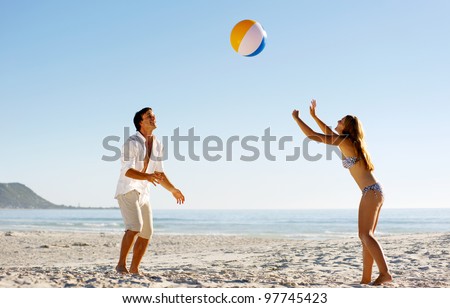 Young couple on a summer beach vacation playing with a beachball and having carefree fun