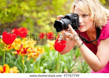 Beautiful woman taking photographs of tulips in a spring garden
