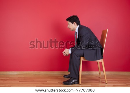 Businessman sited next to a red wall